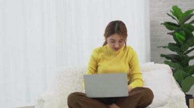 Güzel Asyalı kız internetten kredi kartıyla alışveriş yapıyor ve gülümsüyor. Bilgisayarları kullanan ve internet üzerinden online alışveriş yapan kadınlar, evde kredi kartıyla online alışveriş fikirleri.