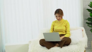Güzel Asyalı kız internetten kredi kartıyla alışveriş yapıyor ve gülümsüyor. Bilgisayarları kullanan ve internet üzerinden online alışveriş yapan kadınlar, evde kredi kartıyla online alışveriş fikirleri.