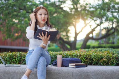 Asyalı öğrenciler ev dışında internet üzerinden çalışmak için dizüstü bilgisayar kullanıyorlar. açık hava öğrenimi ve çalışma konsepti