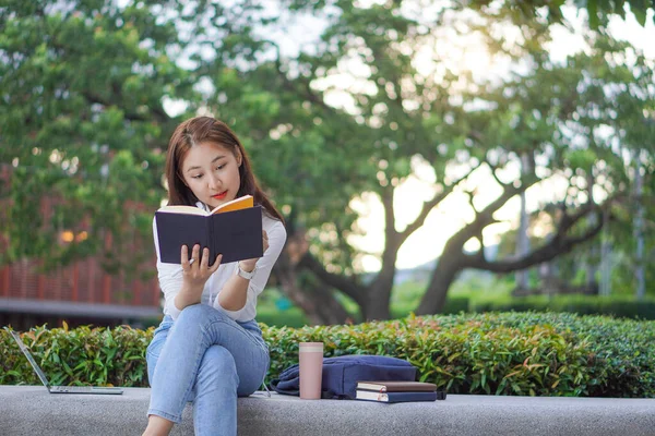 Asyalı öğrenciler ev dışında internet üzerinden çalışmak için dizüstü bilgisayar kullanıyorlar. açık hava öğrenimi ve çalışma konsepti