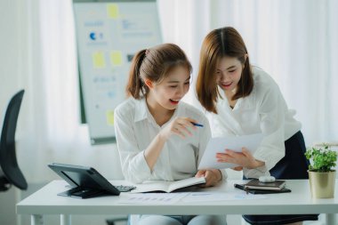 İki genç Asyalı iş kadını toplantı odasında modern bir ofiste başarılı bir başlangıç için beyin fırtınası yapıyorlar..