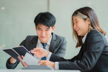İki genç Asyalı iş adamı konferans odasında başarılı bir modern ofis kurma konusunda fikir alışverişinde bulunuyor..