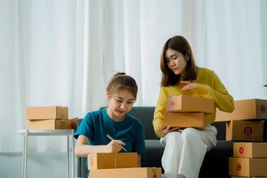 İki Asyalı kız iş kuruyor. KOBİ 'ler başarılı modern ofis teslimatları için paket kutularıyla çalışıyorlar.