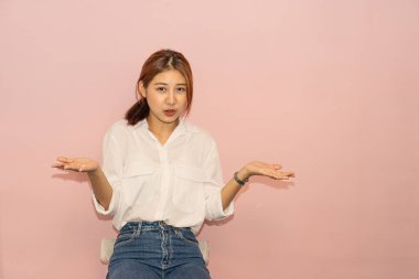 Beyaz elbiseli, siyah saçlı, tatlı Asyalı güzel bir kadının portresi nazik bir gülümsemeyle poz veriyor. Yalnız pembe bir arka planda