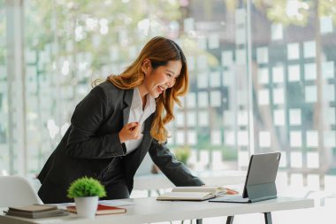 Happy smiling successful Asian businesswoman working on business Go online through the Internet by placing your tablet in front of you.