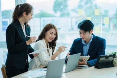 Takım olarak çalışan bir grup Asyalı iş adamı bir finansal tabloyu analiz eder ya da bir pazarlama planını tartışır. Kadın liderler yeni iş stratejileri sunar ve planlarlar. takım çalışması konsepti