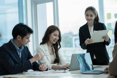 Takım olarak çalışan bir grup Asyalı iş adamı bir finansal tabloyu analiz eder ya da bir pazarlama planını tartışır. Kadın liderler yeni iş stratejileri sunar ve planlarlar. takım çalışması konsepti