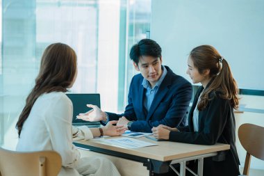 Takım olarak çalışan bir grup Asyalı iş adamı bir finansal tabloyu analiz eder ya da bir pazarlama planını tartışır. Kadın liderler yeni iş stratejileri sunar ve planlarlar. takım çalışması konsepti