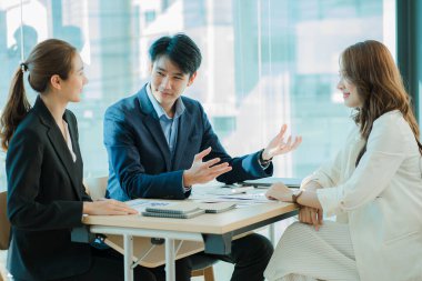 Takım olarak çalışan bir grup Asyalı iş adamı bir finansal tabloyu analiz eder ya da bir pazarlama planını tartışır. Kadın liderler yeni iş stratejileri sunar ve planlarlar. takım çalışması konsepti