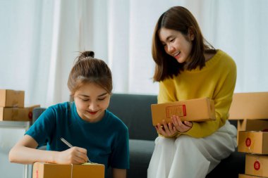 Serbest çalışan 2 Asyalı kız KOBİ 'nin iş bürosu müşterilerin siparişlerini düzenlemek ve kontrol etmek ve paket kutularıyla paketleme için çevrimiçi dağıtım.