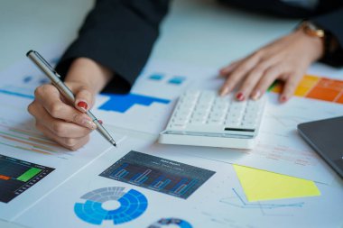 Bir finans ve hesap makinesi işadamı ve emlak yatırım maliyetleri ve diğer vergi sistemlerinin grafiklerini analiz ediyor. bir dizüstü bilgisayarla