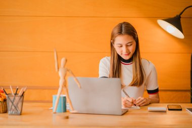 Güzel Asyalı kadın muhasebecinin evde dokümanları kontrol ederken, defter ve hesap makinesi kullanırken çekilmiş bir fotoğrafı. Evde mutlu mesut gülümsüyorum..