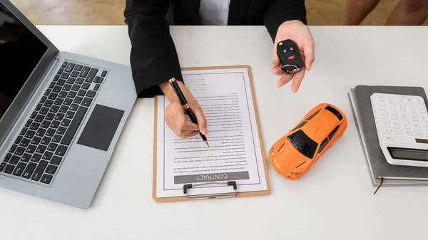 The car salesman hands the keys to the customers who have signed the legal car sales contract. Sell the finished car and deliver the keys at the table in the top view sales office.