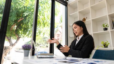 An Asian businesswoman with pain in her hands from accounting work analyzes charts and graphs of market dynamics by using laptops and calculators at company desks to read financial charts