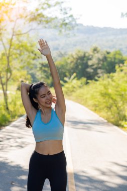 Asyalı kadınlar iyi sağlık için egzersiz yapmadan önce esner. Açık hava parkında uzanırken yatay görüntü. Dişi bir koşucu akşam koşusu ve koşu için ısınıyor..