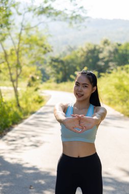 Asyalı kadınlar iyi sağlık için egzersiz yapmadan önce esner. Açık hava parkında uzanırken yatay görüntü. Dişi bir koşucu akşam koşusu ve koşu için ısınıyor..