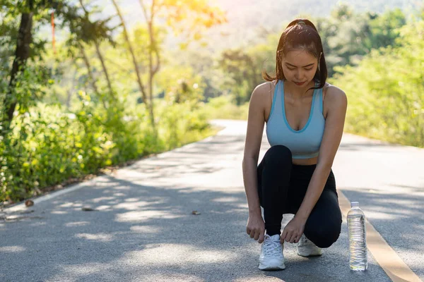 公園でランニングに行く前に靴を結ぶアジアの女性 アウトドアジョギングフィットネスコンセプト — ストック写真