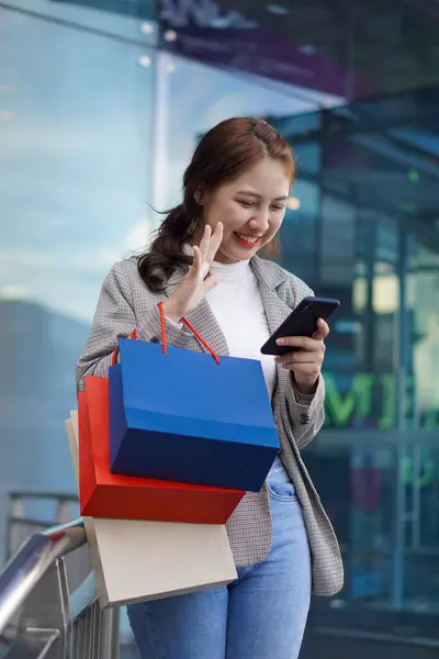 亚洲女孩提着一个包在商场购物时使用你的智能手机 一个漂亮的女孩在商场前购物后尽情享受购物的肖像 — 图库照片