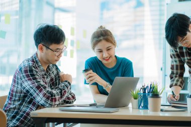 Bir grup Asyalı iş adamı dizüstü bilgisayarlarda beyin fırtınası yapıyor. Çalışmaya kararlı Asyalı genç iş adamlarının toplantısı. Yaratıcı iş ekibi ofiste birlikte oturuyor.