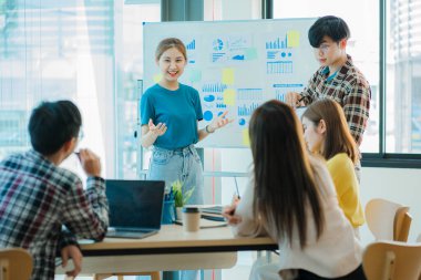 Bir grup Asyalı iş adamı dizüstü bilgisayarlarda beyin fırtınası yapıyor. Çalışmaya kararlı Asyalı genç iş adamlarının toplantısı. Yaratıcı iş ekibi ofiste birlikte oturuyor.