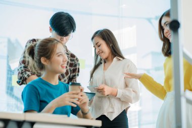 Bir grup Asyalı genç iş adamı yeni nesil yaratıcı genç dizüstü bilgisayarlara beyin fırtınası yapıyor. Toplantıda yeni başlatılan projeler için fikir alışverişinde bulunun ve tartışın.