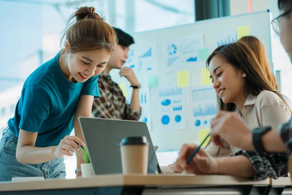 Bir grup Asyalı genç iş adamı yeni nesil yaratıcı genç dizüstü bilgisayarlara beyin fırtınası yapıyor. Toplantıda yeni başlatılan projeler için fikir alışverişinde bulunun ve tartışın.