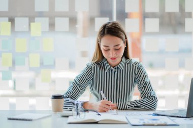 Asyalı iş kadını, matematik, vergi, muhasebe, istatistiksel raporlar ve analitik araştırma fikirlerinden para kazanmak için dizüstü bilgisayarını kullanıyor. Modern ofis gayrimenkul yatırım bilgileri
