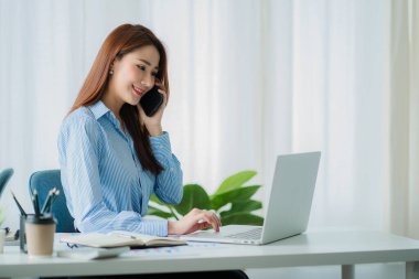 Asian businesswoman using her laptop calculator to make money on her desk math, tax, accounting, statistical reports, and analytical research ideas. Modern office real estate investment information