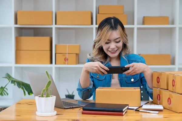 Küçük bir işletme kurmak, KME girişimcileri veya serbest çalışanlar. Asyalı kadınlar kutularla birlikte dizüstü bilgisayar kullanıyorlar ve telefon kullanabiliyorlar. İş yerinde başarılı kadınlar Sevkiyat, paketleme, çevrimiçi pazarlama