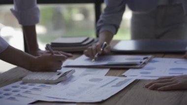 Genç girişimciler buluşup yeni belge projeleri üzerinde fikir alışverişinde bulundular. Birlikte, finansal grafiği analiz edin, takım olarak çalışarak başarı için bir strateji planlayın, yakın plan..