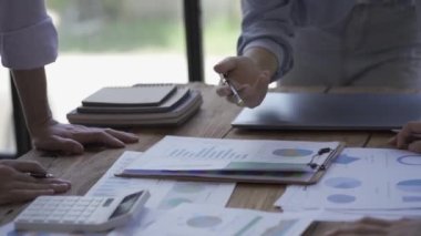 Genç girişimciler buluşup yeni belge projeleri üzerinde fikir alışverişinde bulundular. Birlikte, finansal grafiği analiz edin, takım olarak çalışarak başarı için bir strateji planlayın, yakın plan..