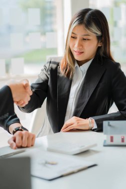 Emlak satış temsilcileri iş dünyasından müşterilerle el sıkışıyor ve mevcut satın alma ve kiralama olanaklarını sunuyorlar. Satış temsilcileri ev projeleri sunuyor. Fikirler Alınıyor ve Kiralanıyor