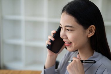 Ofiste Sam 'in telefonu ve laptopuyla çalışan Asyalı kadın çalışan, mali muhasebe kavramı..