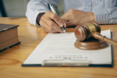 Hukuk Danışmanı Avukatı, yasal kaplan derisi ve adaletsizlik tanrıçası pullarıyla ofis belgeleri üzerinde çalışıyor..