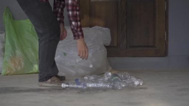 Geri dönüşüm ya da tam gelir olarak satmak için temiz plastik şişe toplayan bir gencin 4K videosu..