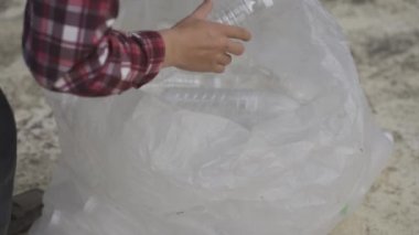 Geri dönüşüm ya da tam gelir olarak satmak için temiz plastik şişe toplayan bir gencin 4K videosu..