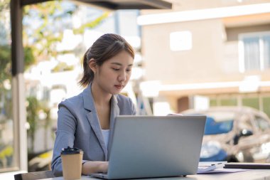 Genç Asyalı iş kadını, parlak, modern bir ofiste elinde hesap makinesiyle dizüstü bilgisayarla çalışıyor. Tabloları, iş planlarını, yatırımları, mali veya muhasebe kavramlarını analiz etmeyi planlamak.