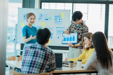 Bir grup Asyalı genç işadamı, yeni proje fikirlerini sunarak çalışmalarını tartışıyor ve tartışıyorlar. Toplantıda pazarlama ve yatırım planlarının analizi