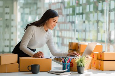Küçük bir iş kurma, serbest KOBİ girişimcisi, evde kutu ve dizüstü bilgisayarla çalışan genç bir kadının portresi, çevrimiçi satış, pazarlama, ambalaj, nakliye, b2b, KME, eCommerce konsepti.