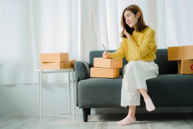 Küçük bir iş kurma, serbest KOBİ girişimcisi, evde kutu ve dizüstü bilgisayarla çalışan genç bir kadının portresi, çevrimiçi satış, pazarlama, ambalaj, nakliye, b2b, KME, eCommerce konsepti.