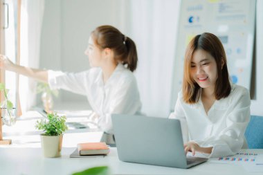 İki güzel Asyalı genç iş adamı dizüstü bilgisayarlarıyla bir masada oturup yeni projenin mali raporlarını tartışmak için evrak işleriyle uğraşıyorlar. Yeni nesil iş birliği kavramı