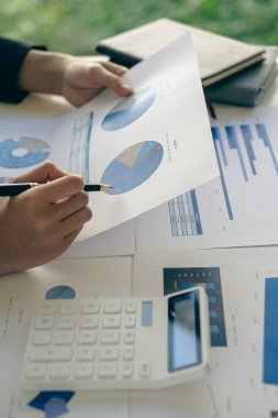 Finansal konsept yakın plan iş adamı elinde bir grafik kalem ile hesap makinesine basar ve rapor yazarak, notlar yazarak ve dikey görüntü iş belgelerini analiz ederek para kazanır..