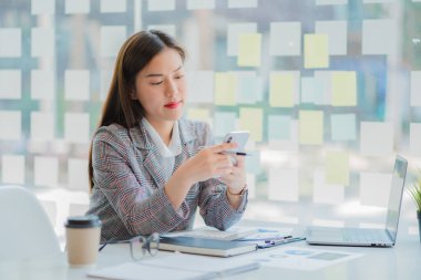 Asyalı iş kadını, şirketinin mali sonuçlarını ve bütçesini hesaplamak için bir hesap makinesi kullanıyor. Modern bir ofis mali ve vergi sisteminde tablet bilgisayarda denetim kavramı
