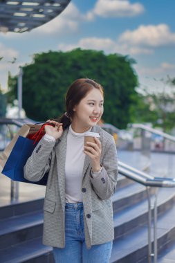 Alışveriş merkezinin önünde duran mutlu Asyalı kadın. - Evet. Alışveriş torbaları tutan Asyalı kadın, kadın konsept alışveriş standı ve dikey olarak elinde çok renkli kağıt torbalar..