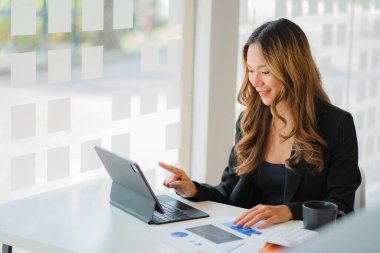 Belgeler ve tablet üzerinde çalışan Asyalı işkadını hesap analizleri emlak yatırımı bilgisini mali ve vergi sistemi kavramlarını rapor ediyor