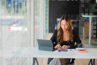 Belgeler ve tablet üzerinde çalışan Asyalı işkadını hesap analizleri emlak yatırımı bilgisini mali ve vergi sistemi kavramlarını rapor ediyor