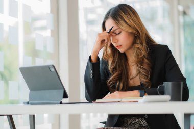 Asyalı iş kadınları iş için tablet kullanıyor ve saatlerce ekrana bakıyor.