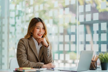 Ofiste bilgisayar başında oturan Asyalı çekici iş kadını Milli Gelir İdaresi belgelerindeki miktarın hesaplanması hakkında bir rapor hazırla.