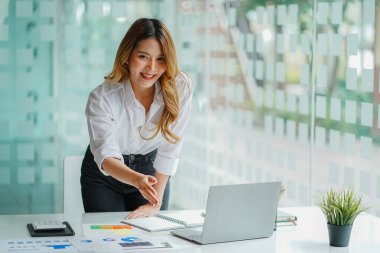Ofiste bilgisayar başında oturan Asyalı çekici iş kadını Milli Gelir İdaresi belgelerindeki miktarın hesaplanması hakkında bir rapor hazırla.