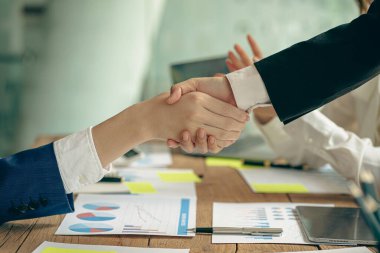 Toplantıda el sıkışan iki iş adamı, bağlantılar, iş ortakları. Hedefler belirledikten ve başarı, ortaklık fikirleri ve takım çalışması planlandıktan sonra grafik kağıdı ve notlarla.